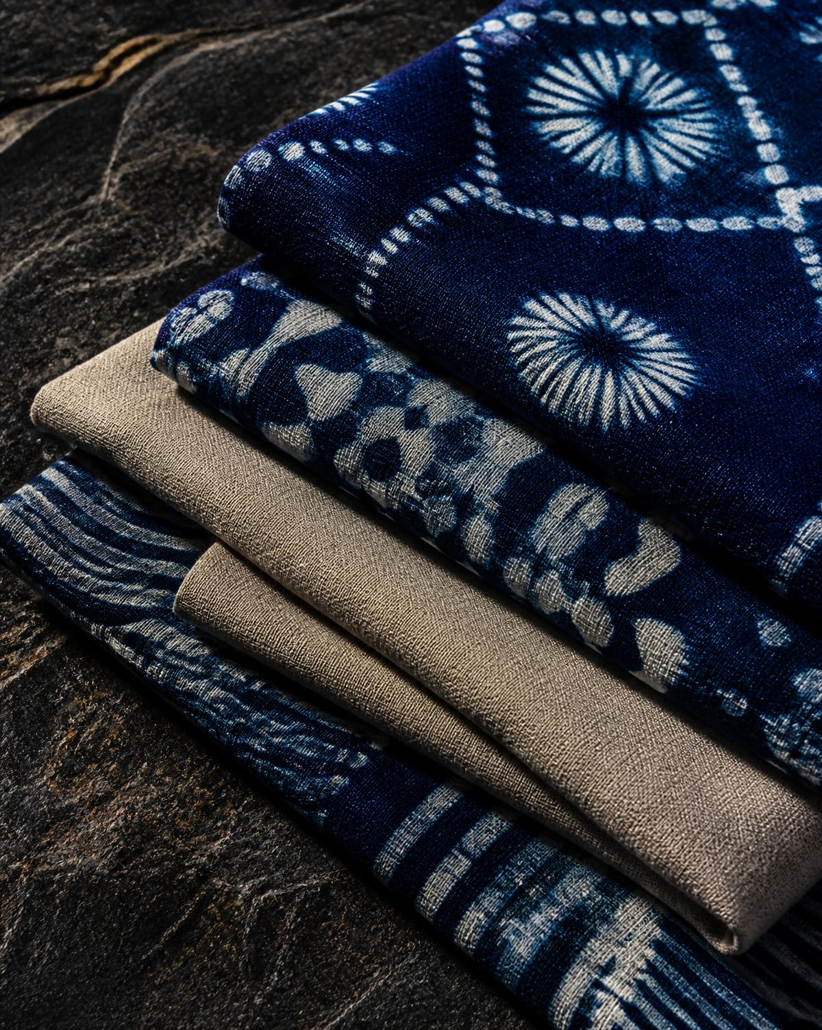 Indigo adire and stone linen cloth folded on dark stone